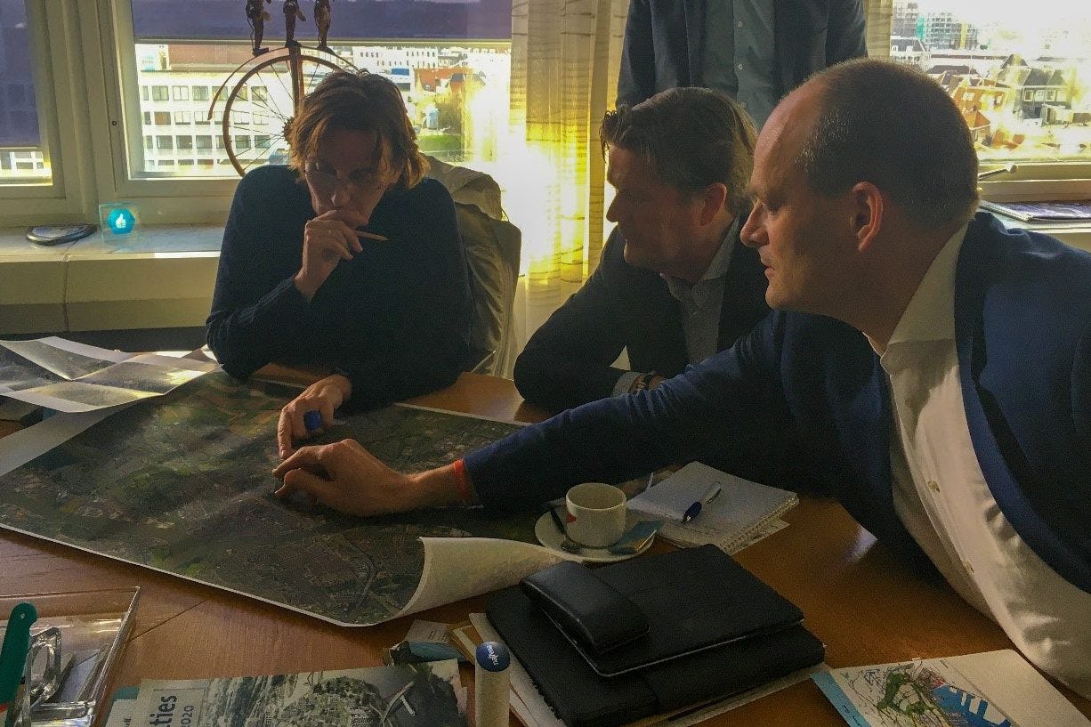 

Francine Houben van Mecanoo buigt zich met de wethouders Piet Sleeking en Rik van der Linden over de spoorzone.
De foto dateert van voor de anderhalve-meter maatregel in de strijd tegen het coronavirus. 