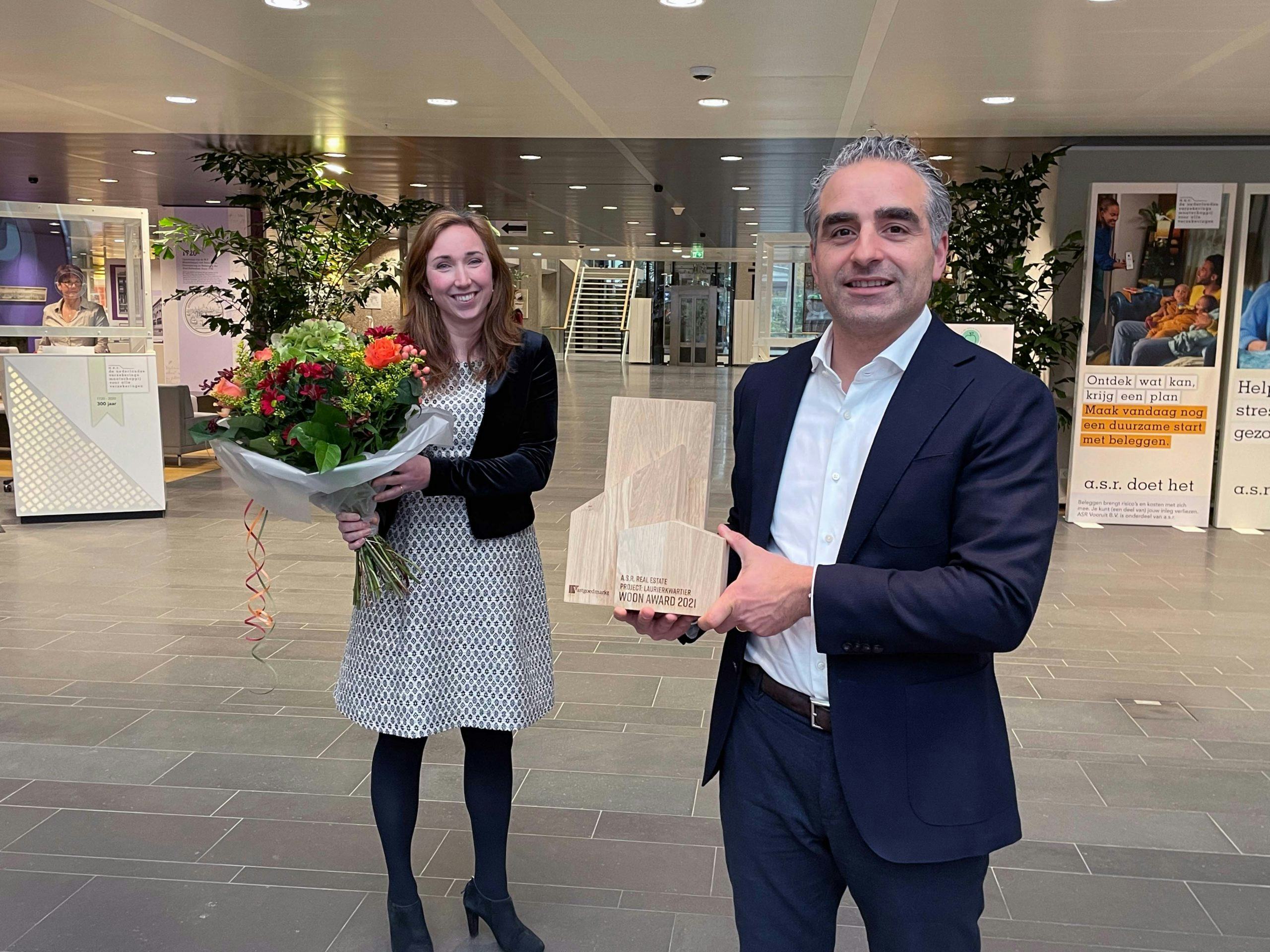 Eva Koppelaar (AM) en Kenny Zartarian (ASR Real Estate) nemen de bloemen en de award in ontvangst.
