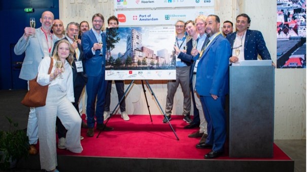 Foto: Dries Drogendijk, wethouder Steven van Weyenberg en vertegenwoordigers van de ontwikkelpartners tijdens het tekenmoment op de Provada, bij de stand van de Metropoolregio Amsterdam.