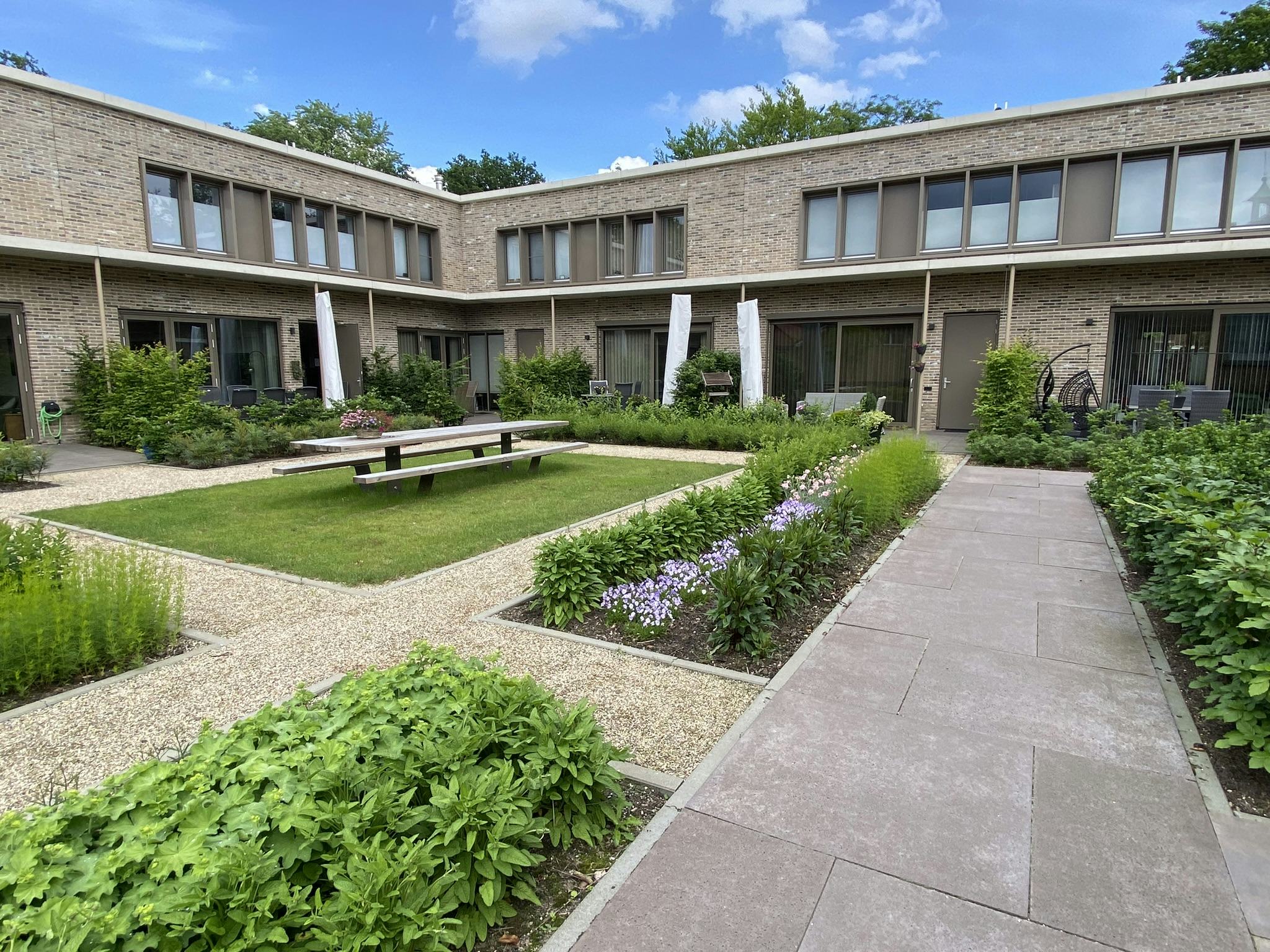 De Hooge Riet, Ermelo. Kleine privé tuinen grenzen aan de gezamenlijke binnentuin, wat de plek is om te ontmoeten en die gezamenlijk door bewoners wordt onderhouden